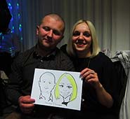 девушка блондинка в черном с парнем
          в ресторане на корпоративе показывают шарж