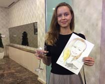 Карина держит свой шарж и бокал вина